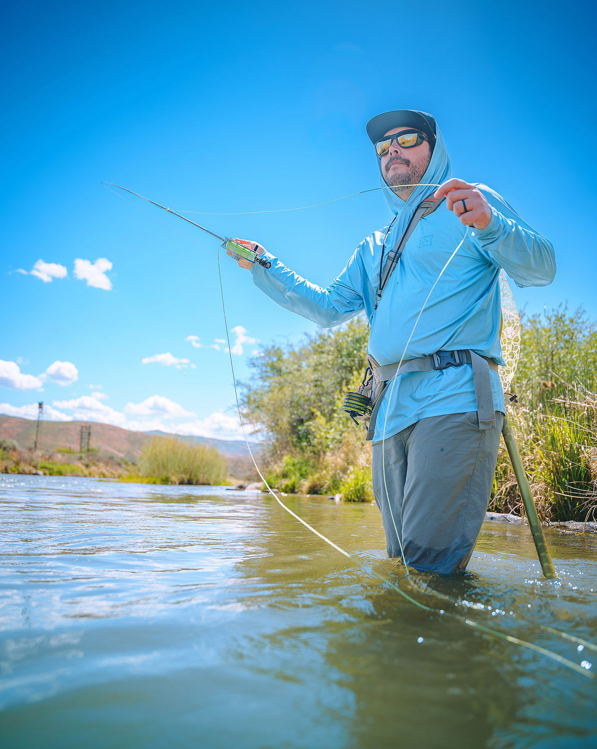 vAngler fly fishing with a Hardy Firecrest fly rod while wading in a river.