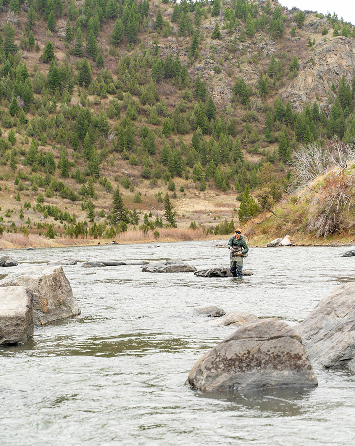 Angler fly fishing in a rocky mountain river with a Hardy Firecrest fly rod.
