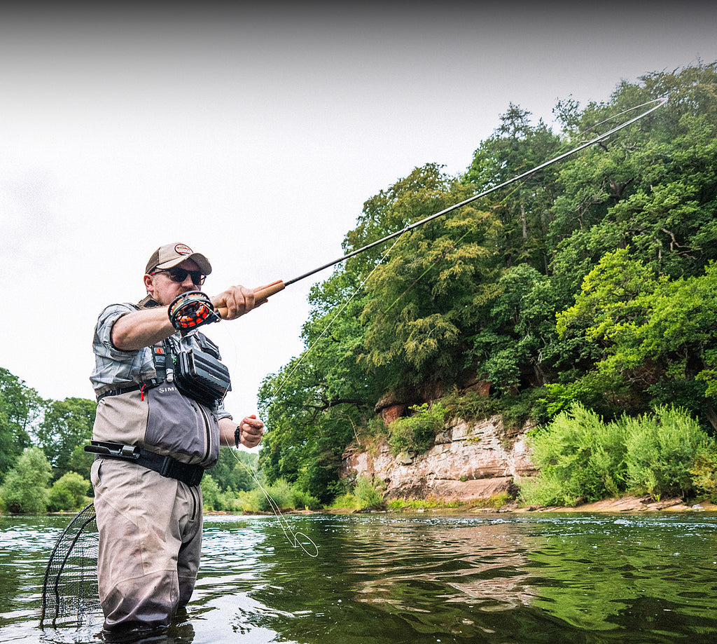 Angler fly fishing in a river with a Hardy Tactus fly rod and reel.