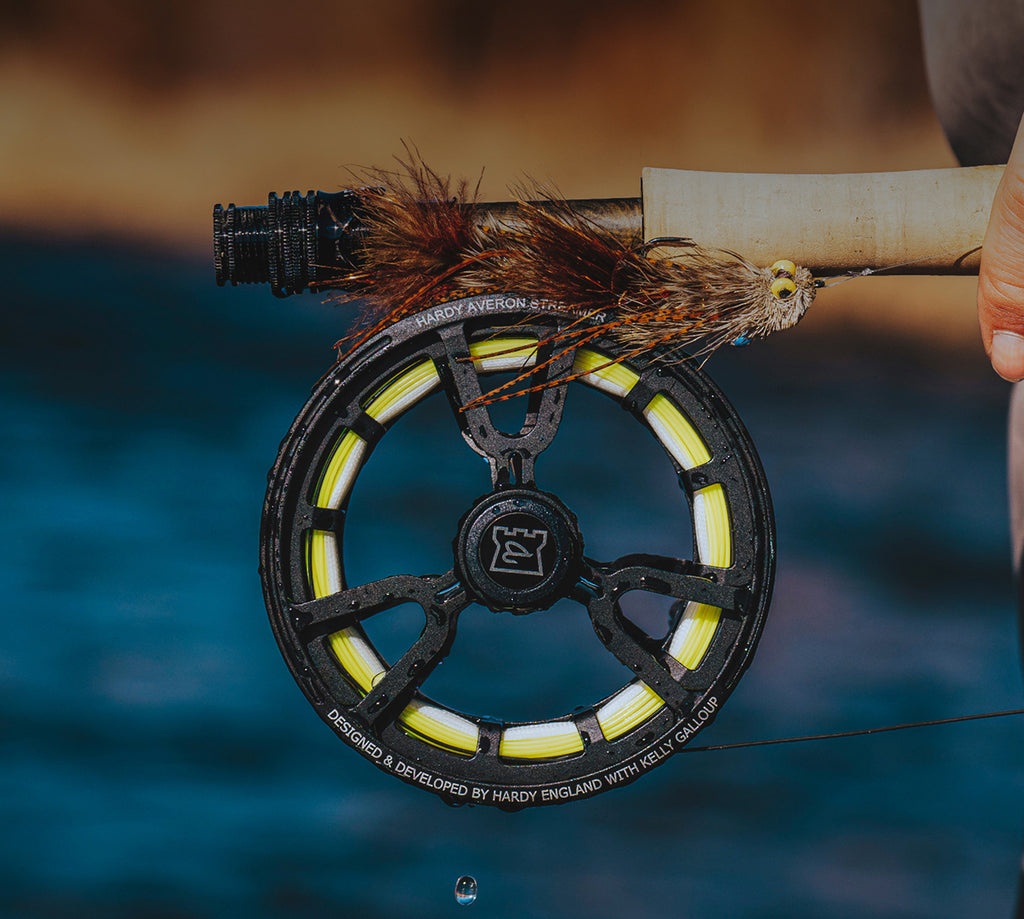 Fishing reel with fly fishing lure against a blurred water background